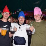 Drei junge Leute auf einer Feier mit Zipfelmützen.