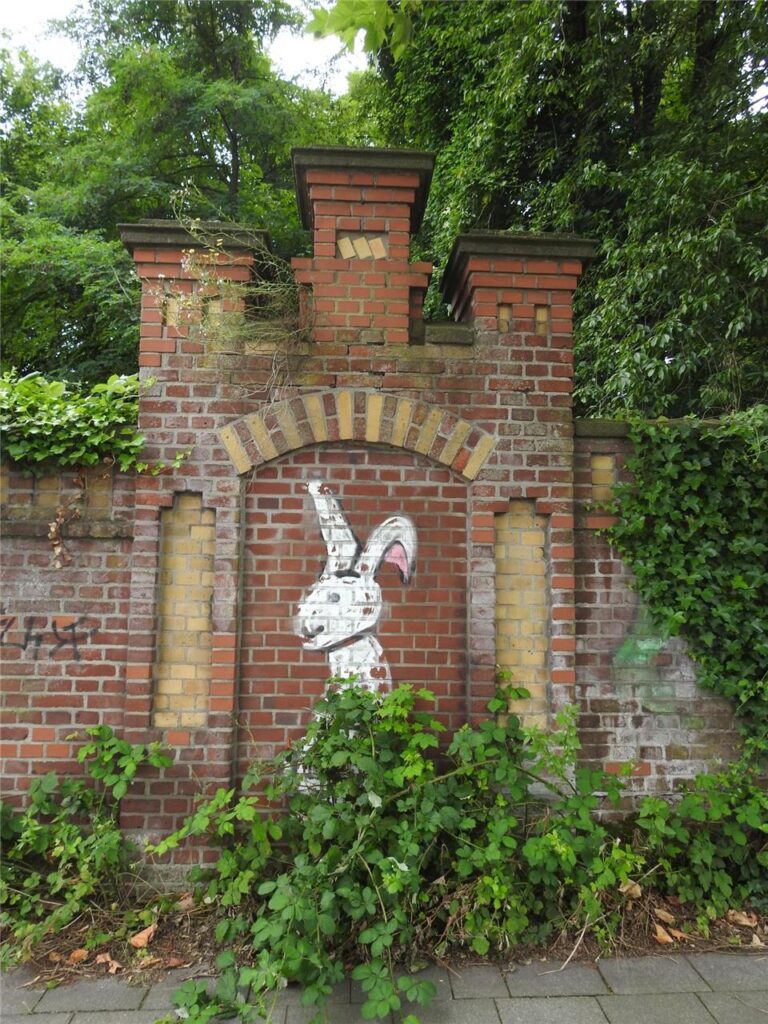 Mit Graffiti versehene, mit drei Türmchen bekrönte Fußgängerpforte der ehemaligen Zechenmauer an der Ecke Suderwich- und Katharinenstraße in Recklinghausen.