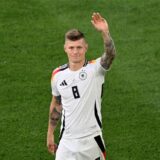 Fußballer Toni Kroos winkt auf dem Spielfeld im weißen Trikot der Deutschen Nationalmannschaft.