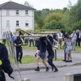 Jugendliche Randalierer werfen einen Teil eines Zauns auf die Polizei während einer Demonstration gegen Einwanderung in der Nähe des Holiday Inn Express Hotel, in dem Asylbewerber untergebracht sind.