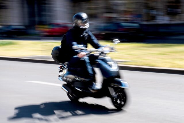 Ein Rollerfahrer fährt auf der Straße.