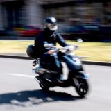 Ein Rollerfahrer fährt auf der Straße.