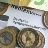 Münzen und Geldscheine liegen auf einer Renteninformation der Deutschen Rentenversicherung.