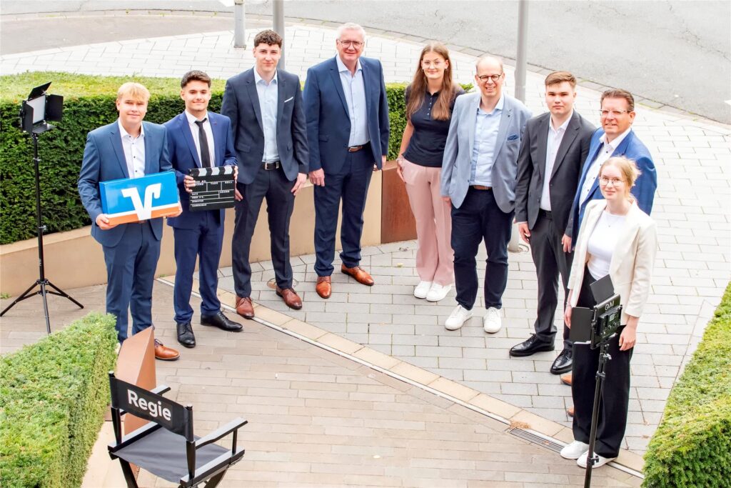 Mehrere Personen stehen im Halbkreis mit einem Schild der Vereinten Volksbank in der Hand. Mehrere Personen stehen im Halbkreis mit einem Schild der Vereinten Volksbank in der Hand.