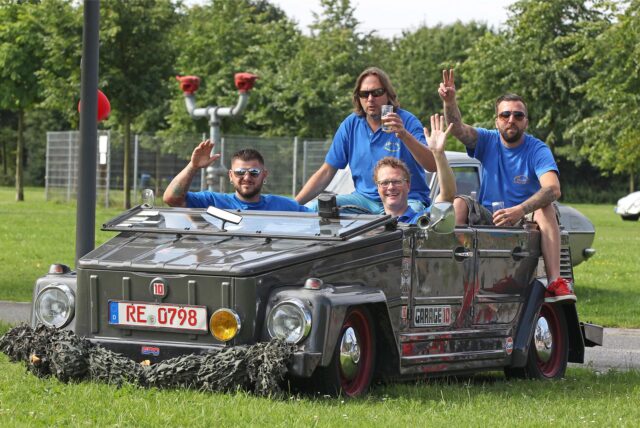 Vier Männer sitzen in einem Kübelwagen von Volkswagen.