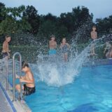 Kinder springen vom Block ins Schwimmerbecken