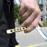 Großaufnahme eines Klappmessers in einer Hand. Die Person, die das Messer hält, ist nicht zu erkennen.