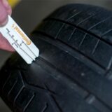 Ein Kfz-Mechaniker misst die geringe Profiltiefe eines abgefahrenen Reifens. (Symbolbild)
