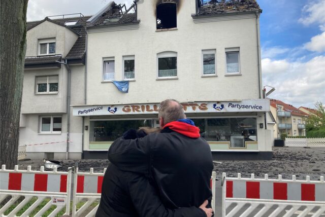 Ein Ehepaar steht vor einem Haus, das durch ein Feuer unbewohnbar geworden ist.
