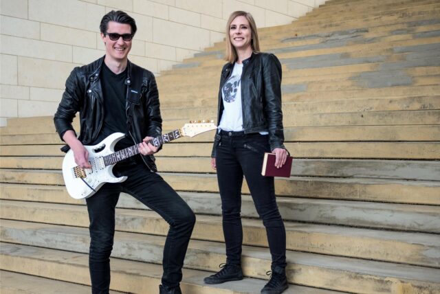 Musiker Ernest und Autorin Pia Lüddecke stehen auf einer großen Treppe.