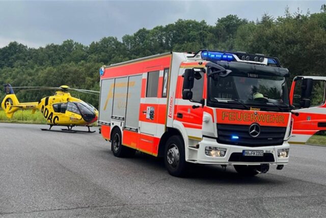 Ein Auto der Feuerwehr Hagen mit dem Rettungshubschrauber Christoph-8 des ADAC im Hintergrund.