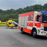 Ein Auto der Feuerwehr Hagen mit dem Rettungshubschrauber Christoph-8 des ADAC im Hintergrund.