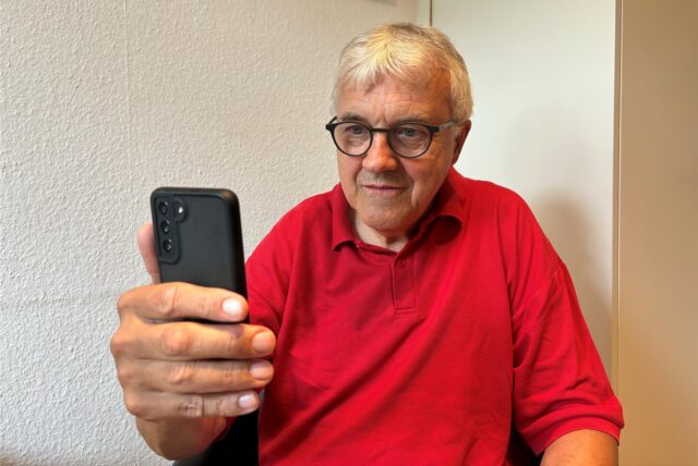 Pfarrer Ludger Ernsting von der Gastkirche in Recklinghausen schaut auf den Bildschirm eines Smartphones.