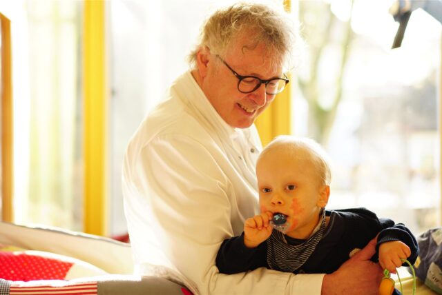 Prof. Dr. Boris Zernikow hält ein kleines Kind auf dem Arm.