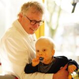 Prof. Dr. Boris Zernikow hält ein kleines Kind auf dem Arm.