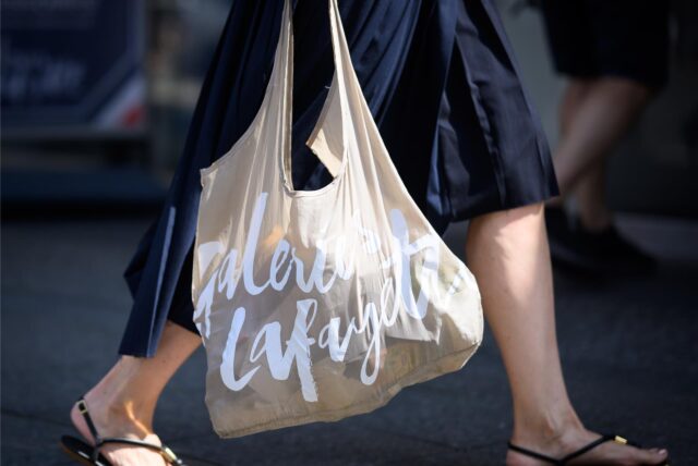 Eine Frau geht am verkaufsoffenen Sonntag mit einer Einkaufstasche shoppen.