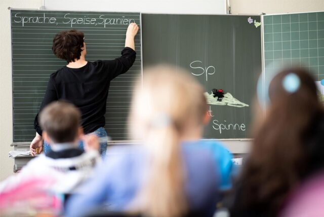 Eine Lehrerin schreibt in einer Grundschule Wörter mit «Sp» am Anfang an eine Tafel.