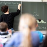 Eine Lehrerin schreibt in einer Grundschule Wörter mit «Sp» am Anfang an eine Tafel.