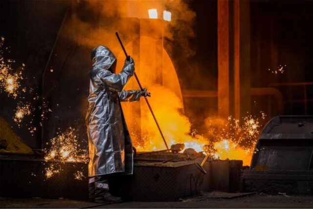 Ein Stahlarbeiter von Thyssenkrupp prüft Roheisen an einem Hochofen.