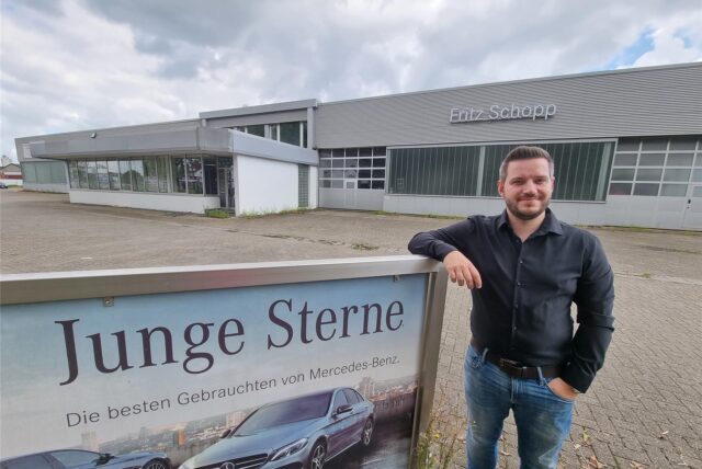 Ein Mann steht vor einem alten Mercedes-Autohaus.
