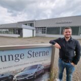 Ein Mann steht vor einem alten Mercedes-Autohaus.