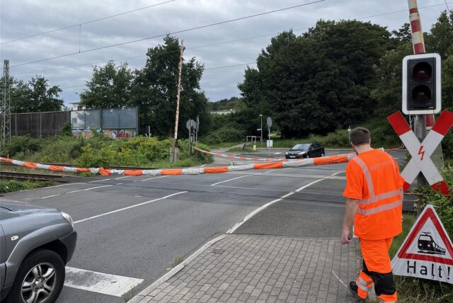 Ein Bahnmitarbeiter hat den Bahnübergang an der Paschenbergstraße in Herten mit einem dicken Seil  anstelle der Schranken abgesperrt, weil in Kürze ein Zug kommen soll.