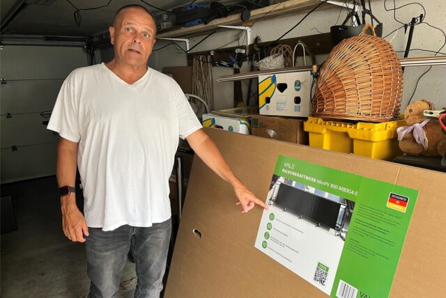 Joachim Michels steht in seiner Garage und zeigt auf das Stecker-Solar-Gerät, was er sich jetzt selbst angescgafft hat.