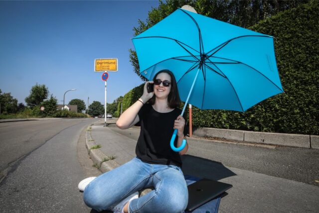 Eine Frau schützt sich in Dortmund mit einem Schirm vor der Sonne.