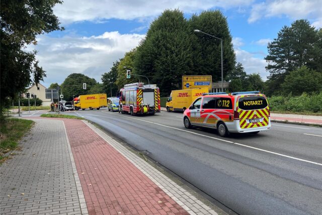 Ein Polizei- und ein Feuerwehrfahrzeug sowie ein Rettungswagen stehen auf der Scherlebecker Straße, in der Entfernung ein demoliertes Lieferfahrzeug und ein demolierter Kleinwagen.