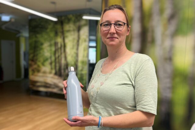 Eine Frau hält eine Trinkwasserflasche in den Händen.