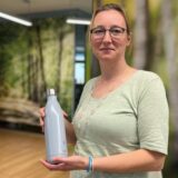 Eine Frau hält eine Trinkwasserflasche in den Händen.