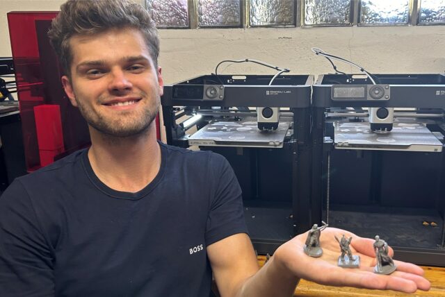 Michael Ruranski hält drei Figuren für Tabletop-Spiele auf der Hand.