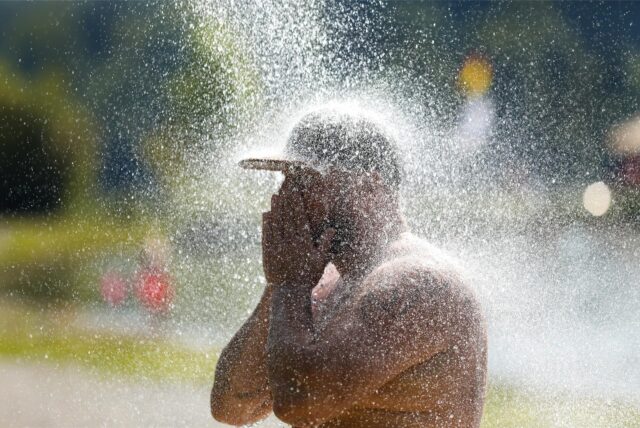 Ein Mann kühlt sich mit Wasser ab.
