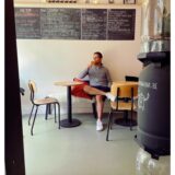 Ein Mann sitzt mit überkreuzten Beinen am Tisch und genießt ein Craft Beer.