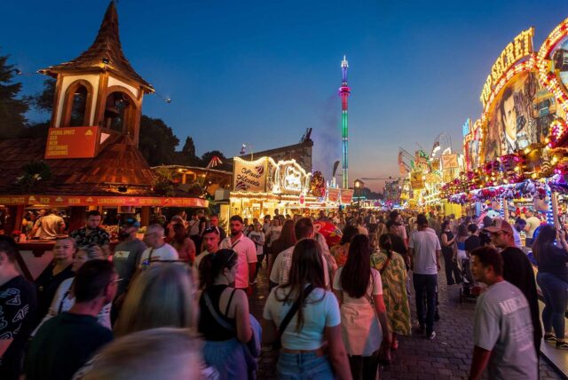 Eine große Menschenmenge läuft über die Cranger Kirmes. Die Sonne ist untergegangen. An den Seiten stehen zahlreiche Stände.
