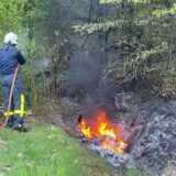 Ein Feuerwehrmann löscht einen Böschungsbrand.