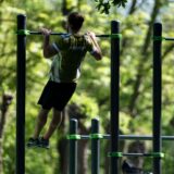 Ein Mann macht Klimmzüge an einer Stange in einem Outdoor-Park.