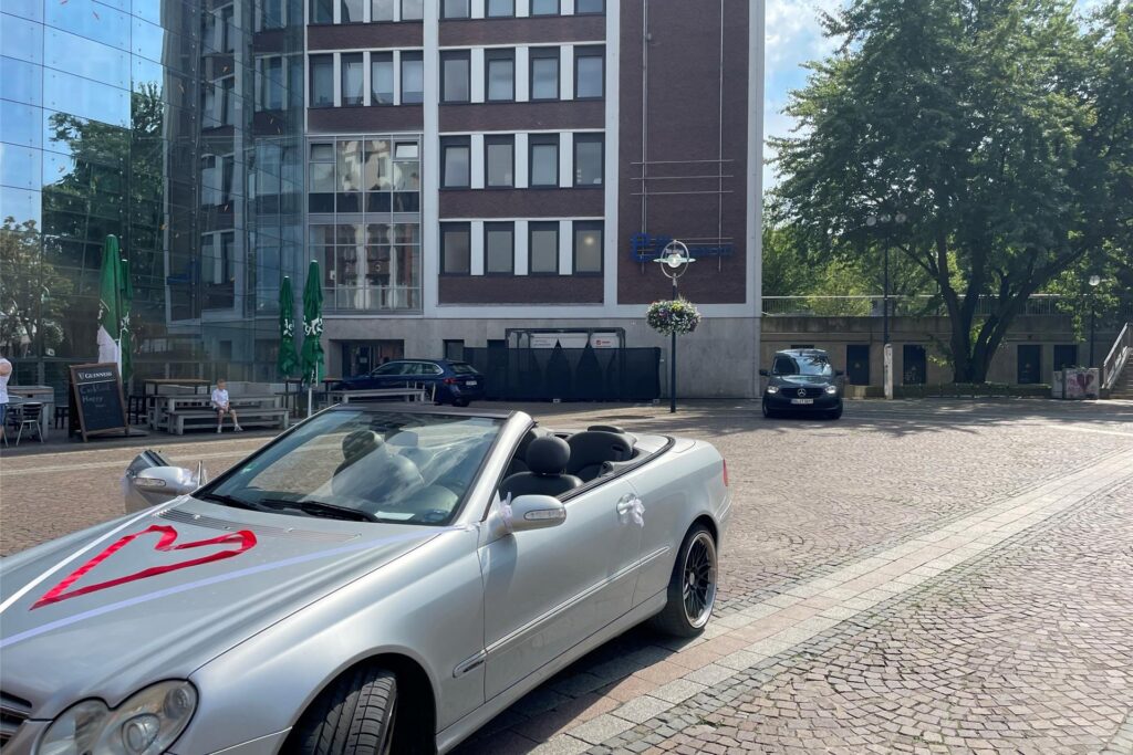 Ein silbernes Cabrio steht auf dem Friedensplatz. Ein Herz ist mit einem roten Band auf der Motorhaube ausgelegt.