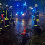 Feuerwehrleute stehen im Dunkeln vor einem Gulli in Dorsten.
