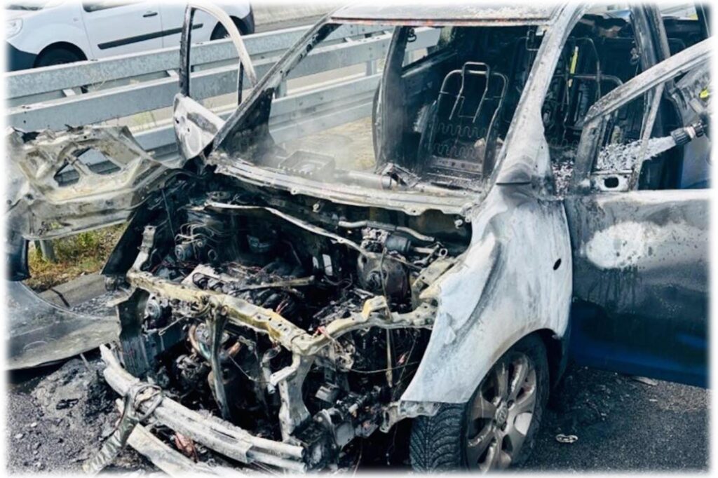 Ausgebrannter Kleinwagen steht auf einer Autobahn.