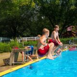 Zwei Kinder springen mit einer Arschbombe ins Wasser im Freibad Mollbeck in Recklinghausen.