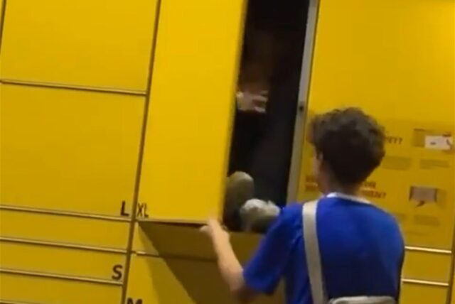 Ein Jugendlicher sitzt im Fach einer Packstation, während ein anderer die Tür schließt.
