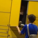 Ein Jugendlicher sitzt im Fach einer Packstation, während ein anderer die Tür schließt.