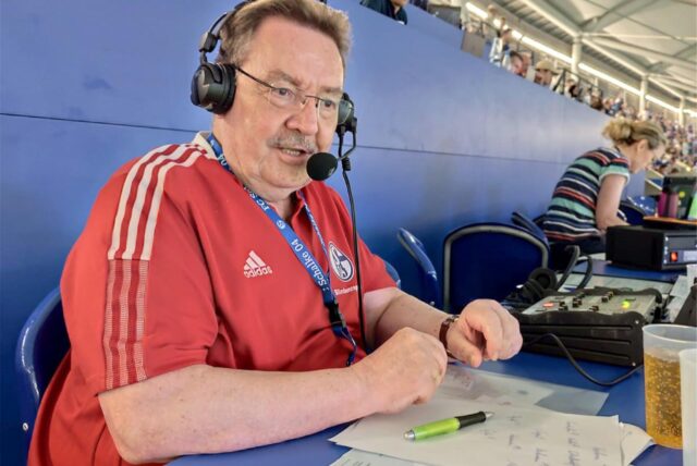Der Hertener Michael Stimpel sitzt auf der Pressetribüne des FC Schalke 04. Er trägt ein Headset und spricht ins Mikrofon.