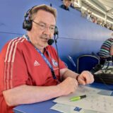 Der Hertener Michael Stimpel sitzt auf der Pressetribüne des FC Schalke 04. Er trägt ein Headset und spricht ins Mikrofon.