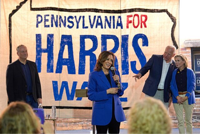 Kamala Harris (M), US-Vizepräsidentin und Präsidentschaftskandidatin der Demokraten, spricht zwischen ihrem Mann Doug Emhoff (l), sowie Vizepräsidentschaftskandidat Tim Walz (2.v.r) und seiner Frau Gwen Walz (r) auf einer Wahlkampfveranstaltung.
