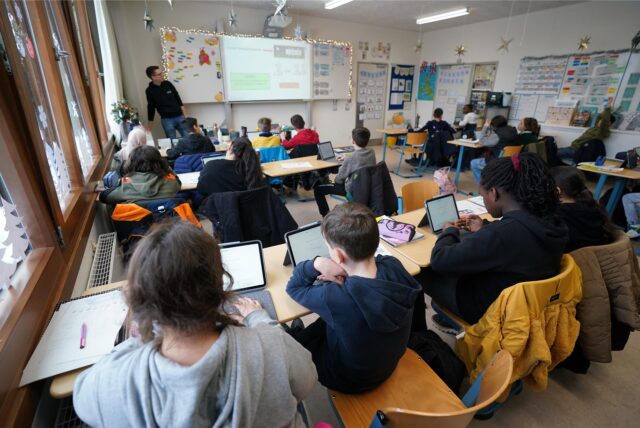 Schüler sitzen vor ihren Tablets in einem Klassenzimmer.