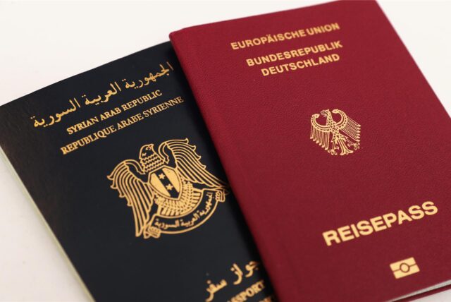 Ein syrischer und ein deutscher Reisepass liegen symbolisch für die doppelte Staatsangehörigkeit nebeneinander.