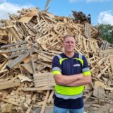 Daniel Otto, Betriebsleiter der neuen Altholz-Aufbereitungsanlage in Datteln, steht vor einem großen Haufen Altholz.