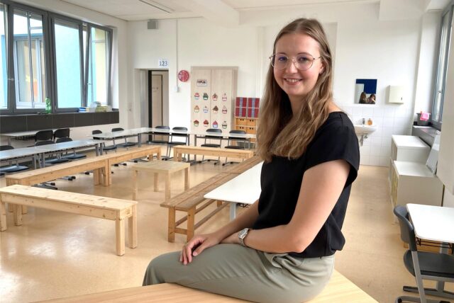 Maria Hoppe sitzt auf dem Pult in ihrem Klassenzimmer 1.23 der Grundschule Herten-Mitte.